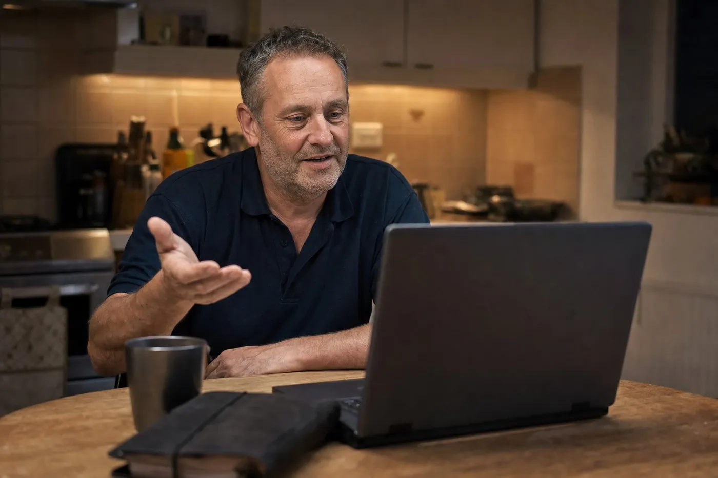 A senior heating engineer at his kitchen table talking on a video call from his laptop